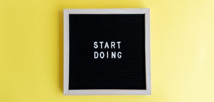 Black message board with 'Start Doing' on a bright yellow background for inspiration.