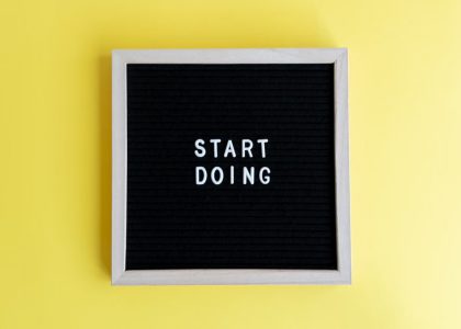 Black message board with 'Start Doing' on a bright yellow background for inspiration.